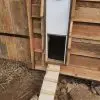 Module de fermeture automatique solaire sur un poulailler en bois avec une porte fabriquée maison.